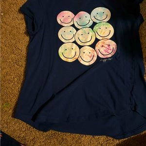 Navy blue shirt with tie dye smiley faces and says happiness